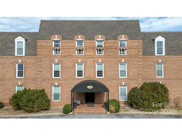 A brick building exterior featuring symmetric windows under a gray roof, with shrubbery and an entrance awning at 300 N Fulton St # 12, Salisbury, NC 28144