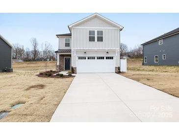Charming two-story home featuring a white garage door, stone accents and a long driveway at 3030 Swallowtail Ln, Kannapolis, NC 28083