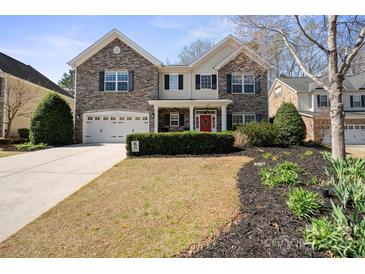 Charming two-story home featuring a stone facade, red door, well-manicured lawn, and an attached two-car garage at 4035 W Sandy Trl, Fort Mill, SC 29707