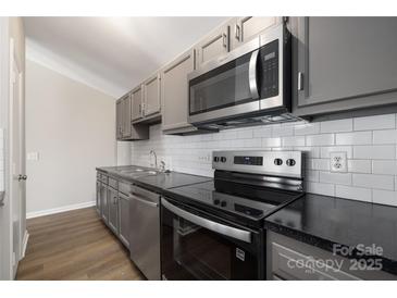 Updated kitchen with stainless steel oven, range, microwave, and dark countertop at 6142 Meadow Rose Ln, Charlotte, NC 28215