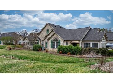 Beautiful stone home with lush green lawn, manicured landscaping, and charming green shutters at 824 Wynnshire Dr # D, Hickory, NC 28601