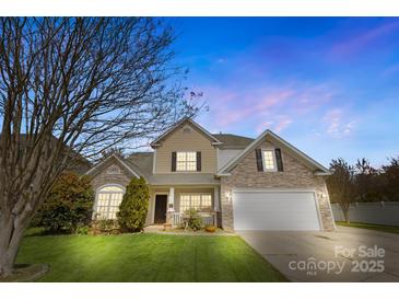Charming two-story home with a stone and tan exterior and well-manicured lawn at dusk at 1016 Filly Dr, Indian Trail, NC 28079
