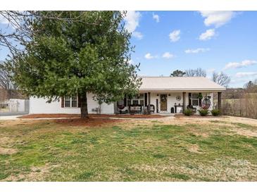 Charming single-story home featuring a metal roof and rocking chair front porch at 24253 Old Aquadale Rd, Albemarle, NC 28001