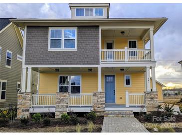 Charming two-story home with a welcoming front porch, stone accents and stylish yellow and gray siding at 283 Luray Way # 449, Rock Hill, SC 29730