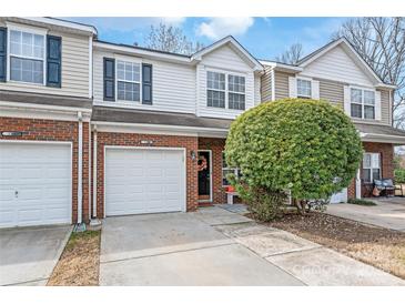 Charming two-story brick townhome featuring an attached garage and front yard landscaping with a mature shrub at 130 Clydesdale Ct, Matthews, NC 28104