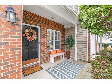 Cozy front porch featuring a brick facade, decorative wreath, and a striped rug over the concrete at 130 Clydesdale Ct, Matthews, NC 28104