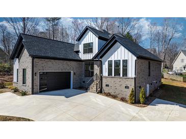 Beautiful new construction home with a gray brick facade, black trim, and a spacious concrete driveway at 4060 Steve Ikerd Ne Dr, Hickory, NC 28601
