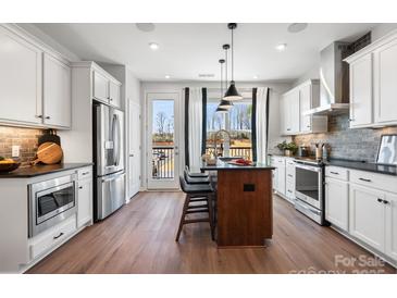 Modern kitchen features white cabinets, stainless steel appliances, and a center island with bar seating at 5731 Castlerea Dr, Charlotte, NC 28217