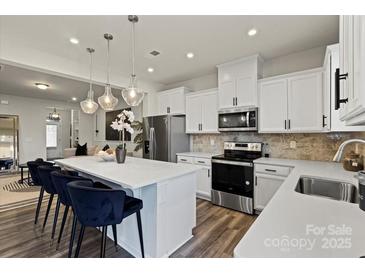 Bright, open kitchen features white cabinetry, stainless steel appliances, and a large island with pendant lighting at 9042 Northfield Crossing Dr, Charlotte, NC 28269