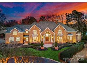 Stunning brick home showcasing manicured landscaping and a grand entrance illuminated by elegant outdoor lighting at 17429 Staysail Ct, Cornelius, NC 28031