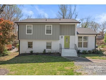Inviting two-story home featuring gray and white brick exterior, lush landscaping, and a bright green front door at 6914 Idlewild Rd, Charlotte, NC 28212