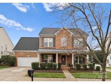 Charming two-story brick home featuring a covered front porch and well-maintained landscaping at 8806 Cool Meadow Dr, Huntersville, NC 28078