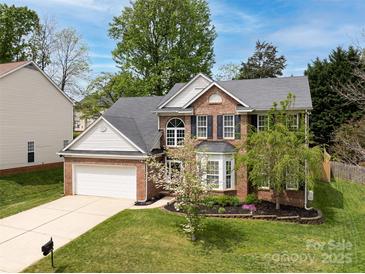 Beautiful two-story brick home featuring a manicured lawn, attached two-car garage, and lush landscaping at 12729 Mcginnis Ln, Huntersville, NC 28078