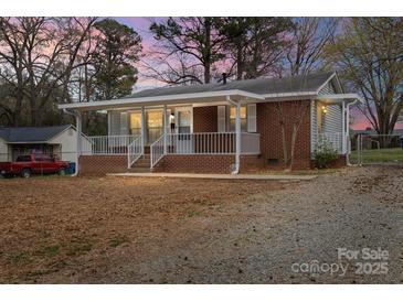 Charming single story home with brick and siding, a covered front porch, and mature trees at 208 Tomberlin Rd, Mount Holly, NC 28120