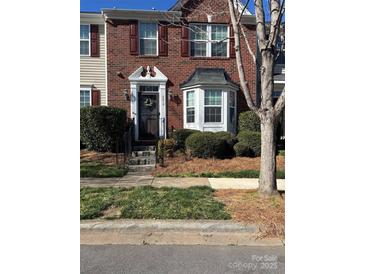 Charming brick townhome featuring a welcoming front door with decorative wreath and bay window at 6410 Hasley Woods Dr, Huntersville, NC 28078