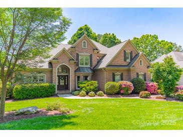 Beautiful brick home featuring professional landscaping and a welcoming front lawn at 13358 Bally Bunnion Way, Davidson, NC 28036