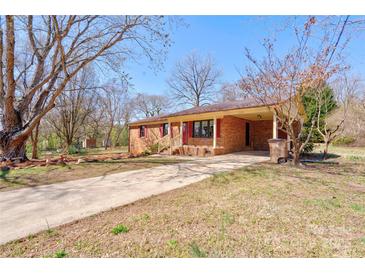 Charming brick home featuring a covered carport and a long driveway, nestled on a tree-filled lot at 200 Southfork Dr, Shelby, NC 28152