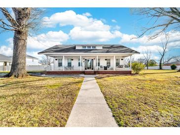 Charming white home featuring a spacious porch with swing and walkway to the front entrance at 308 W First St, Lowell, NC 28098
