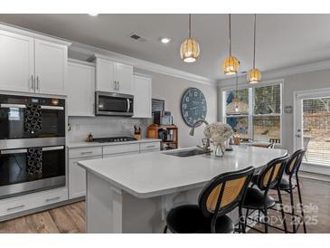 Bright, open kitchen with quartz countertops, modern appliances, and a cozy breakfast bar with seating at 5056 Blue Serenity Ct, Denver, NC 28037