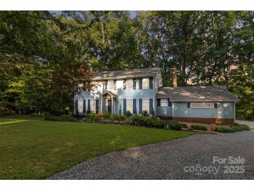 Charming two-story home with light-blue siding, black shutters, and a well-manicured front lawn and garden at 601 Highland Forest Dr, Charlotte, NC 28270