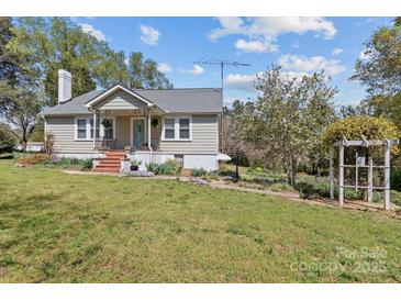 Charming one story home featuring a welcoming front porch, landscaped yard, and lovely blue sky at 10633 Hwy 52 Hwy, Rockwell, NC 28138