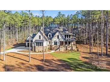 Stunning exterior of a light and stone home nestled among the trees with a manicured lawn at 4354 Persimmon Rd, Lancaster, SC 29720