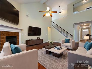 Bright living room with hardwood floors, a fireplace, and comfortable seating beneath a vaulted ceiling at 8830 Beaver Creek Dr, Charlotte, NC 28269