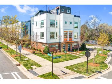 Modern townhome with white siding, brick accents, manicured lawn, and vibrant orange door at 111 W Poindexter Dr, Charlotte, NC 28203