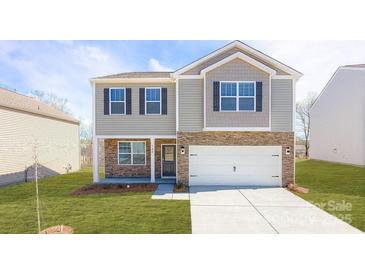Charming two-story home featuring stone accents, neutral siding, dark shutters, manicured lawn, and a two-car garage at 1353 Secrest Commons Dr, Monroe, NC 28112