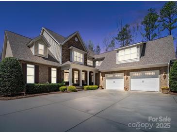 Beautiful brick and stone home featuring a spacious driveway, front porch and a three car garage at 3024 Beaver Dam Dr, Monroe, NC 28110