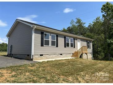 Charming home featuring gray siding, black shutters and well-maintained landscaping at 565 Perry Rd, Troutman, NC 28166