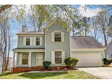 Charming two-story home featuring light blue siding, white shutters, a brick foundation and a well-manicured lawn at 7815 Ambleside Dr, Charlotte, NC 28216