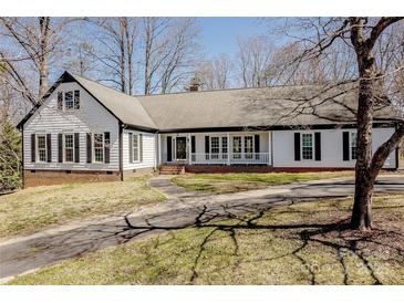 Charming home featuring black shutters, complemented by a well-manicured lawn and long driveway at 10101 Woodview Cir, Charlotte, NC 28277