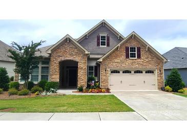 Beautiful stone and siding home with manicured lawn and two-car garage offers great curb appeal at 17436 Langston Dr, Charlotte, NC 28278