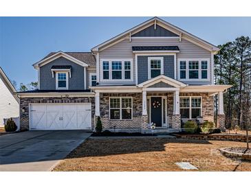 Charming two-story home boasts a stone and siding exterior with a welcoming front porch and a well-manicured lawn at 15606 Walnut Hill Dr, Charlotte, NC 28278