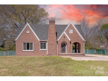 Charming brick home featuring gabled roof lines and an arched entryway, surrounded by a well-maintained lawn at 410 E Arch St, Lancaster, SC 29720