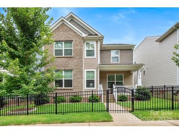 Charming two-story home featuring a brick facade, a black metal fence, and manicured landscaping at 619 R L Stowe Rd, Belmont, NC 28012