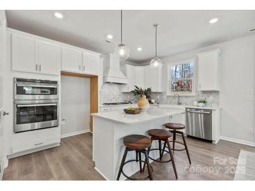 Bright kitchen with white cabinetry, stainless steel appliances, and an island with seating at 162 Holsworthy Dr, Mooresville, NC 28115