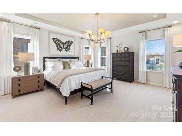 Bright main bedroom featuring a chandelier, large windows, and a dark wood-trimmed bed at 166 Holsworthy Dr, Mooresville, NC 28115