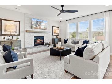 Bright living room with fireplace, large windows, ceiling fan, and modern decor at 173 Holsworthy Dr, Mooresville, NC 28115