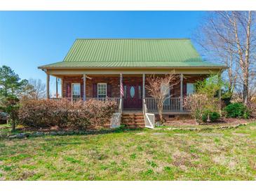 Charming brick home featuring a metal roof and inviting front porch with mature landscaping at 1847 Bertha Knight Rd, Lancaster, SC 29720