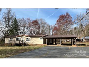 Ranch-style home with a covered carport and deck, nestled on a well-maintained lot with mature trees at 350 Brawley Rd, Cleveland, NC 27013