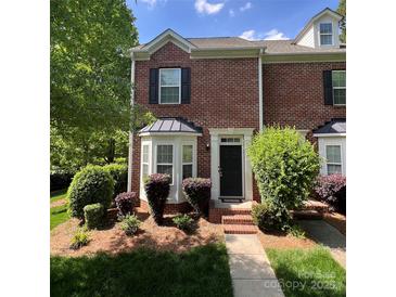 Charming brick townhome with a black front door, manicured landscaping, and bay window at 645 Beaty St, Davidson, NC 28036
