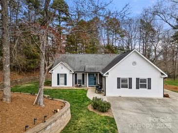 Charming home featuring a blue front door, manicured lawn, and mature trees, providing an inviting curb appeal at 7219 Morningdew Ct, Denver, NC 28037