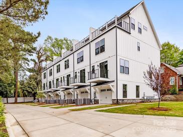 Modern townhome exterior featuring white siding, black trim, private balconies, and individual garages at 1409 Kenilworth Ave, Charlotte, NC 28203