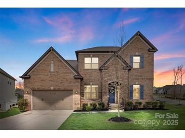 Charming brick home with a two-car garage and manicured lawn at dusk at 3045 Bronwood Pl, Lancaster, SC 29720
