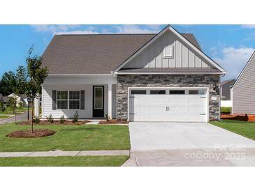 Charming single-story home with stone accents, white garage door, manicured lawn, and inviting entrance at 136 Adams Tree Way, Troutman, NC 28166