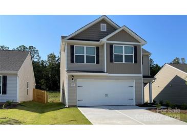 Two-story home featuring attached two-car garage, neutral siding, and manicured lawn at 668 Lamorak Pl, Richburg, SC 29729