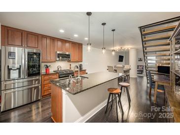 Modern kitchen features stainless steel appliances, granite counters, and sleek dark hardwood flooring at 701 Royal Ct # 102, Charlotte, NC 28202