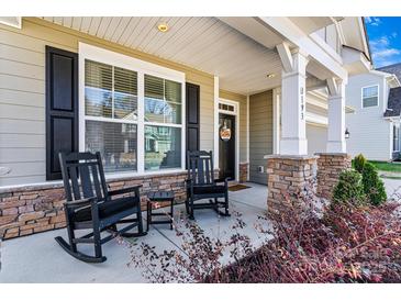 Welcoming front porch with black rocking chairs, stone accents, and stylish shutters at 3193 Burnello Ct, Iron Station, NC 28080